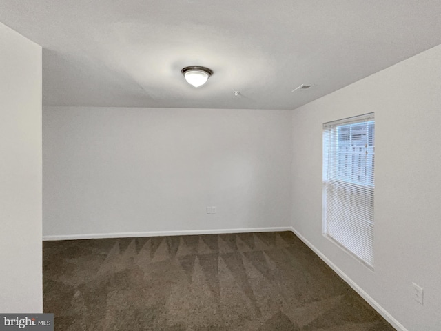 spare room with dark carpet and baseboards