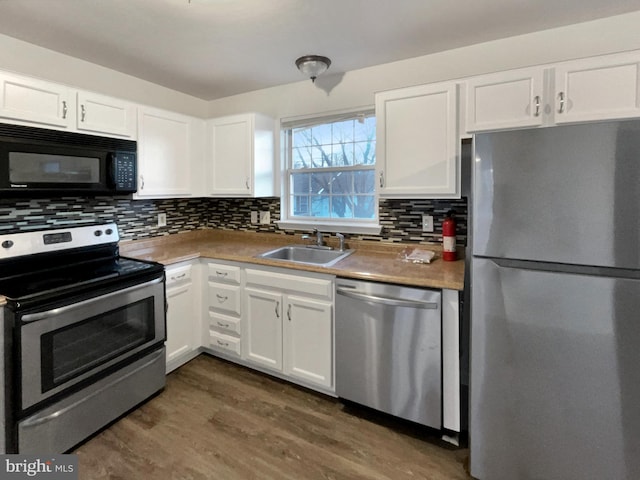 kitchen featuring stainless steel appliances, decorative backsplash, dark wood-type flooring, white cabinetry, and a sink