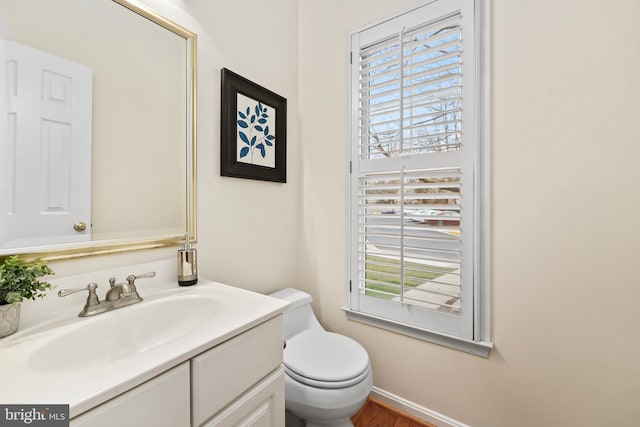 half bathroom with vanity, toilet, and a healthy amount of sunlight