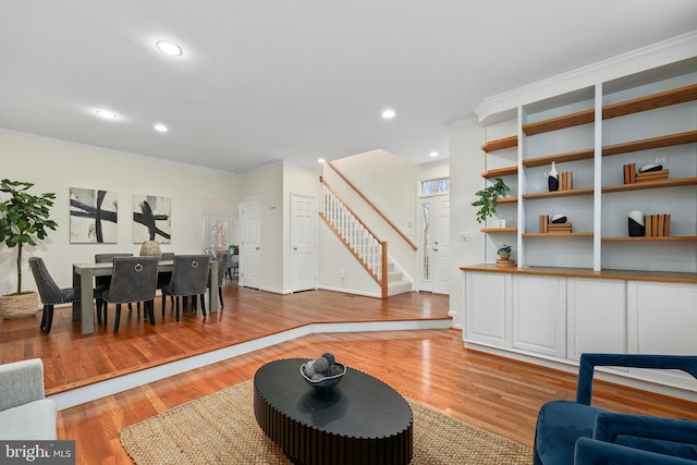 living area featuring baseboards, stairway, light wood-type flooring, ornamental molding, and recessed lighting