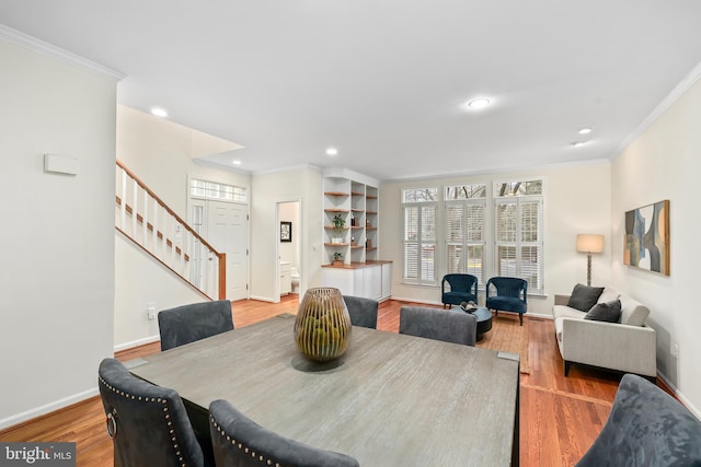 dining space with crown molding, light wood-style flooring, and baseboards