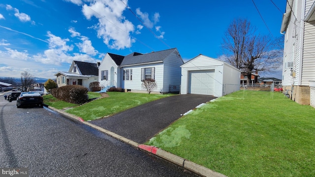 view of front facade with fence, a front lawn, aphalt driveway, and an outdoor structure