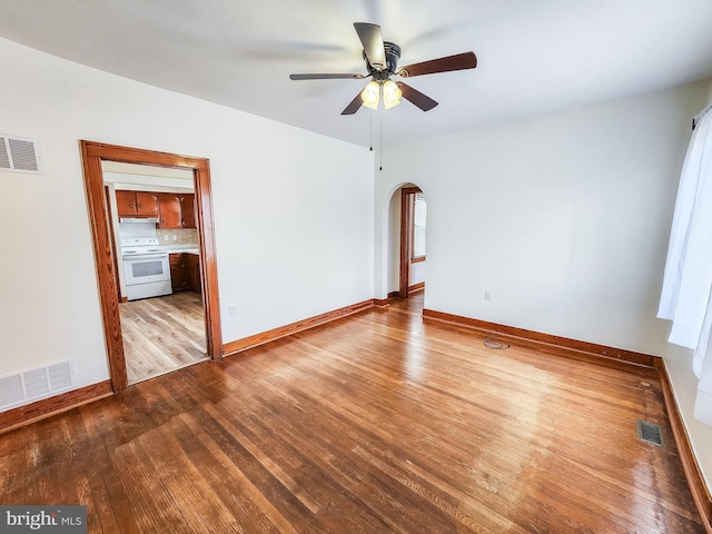 empty room featuring arched walkways, visible vents, and hardwood / wood-style floors