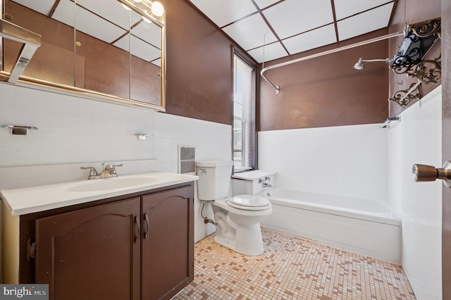 bathroom with tile patterned flooring, tasteful backsplash, tile walls, toilet, and vanity