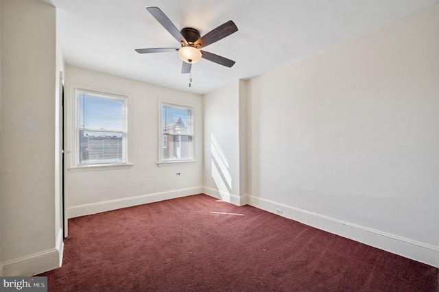 spare room featuring dark colored carpet, baseboards, and a ceiling fan