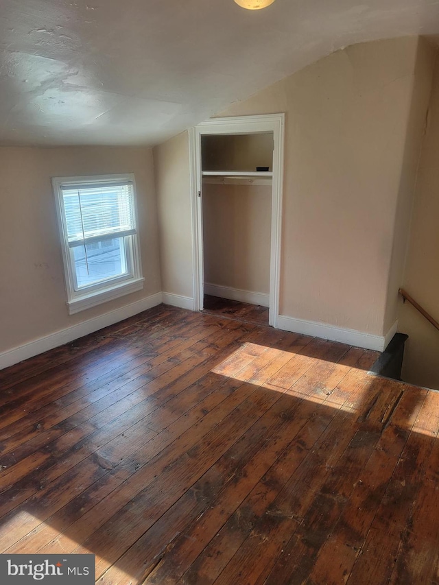 unfurnished bedroom featuring baseboards, wood-type flooring, and a closet