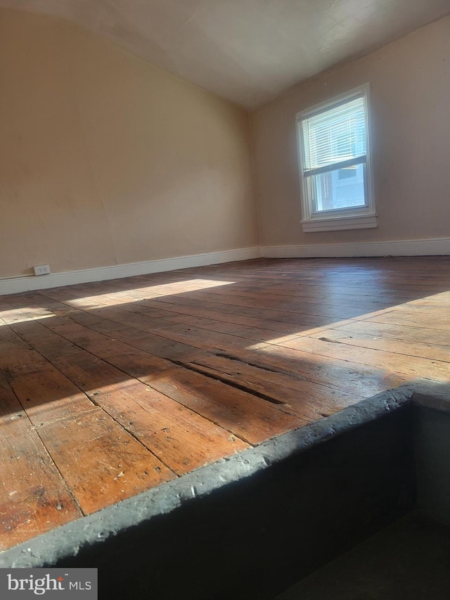 unfurnished room featuring baseboards and hardwood / wood-style floors