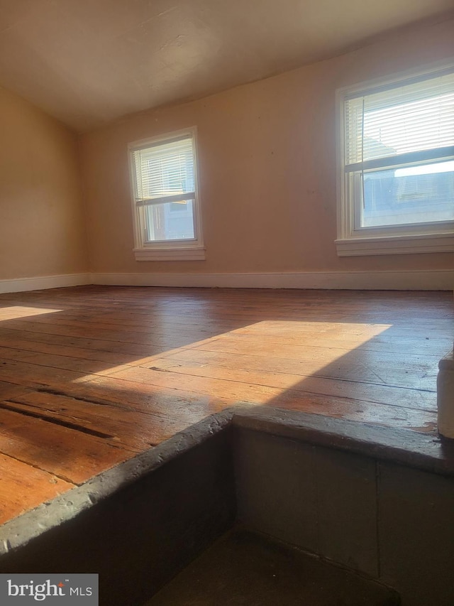 spare room featuring hardwood / wood-style floors, vaulted ceiling, and baseboards