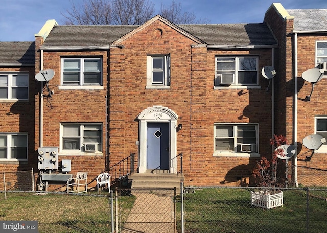 view of property featuring brick siding, a fenced front yard, cooling unit, and a gate