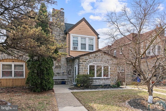 view of front of property with a front yard, stone siding, and roof with shingles