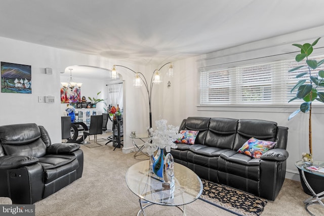 carpeted living room featuring a chandelier and arched walkways