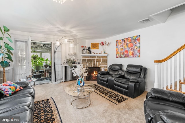 carpeted living area with visible vents, stairway, and a stone fireplace