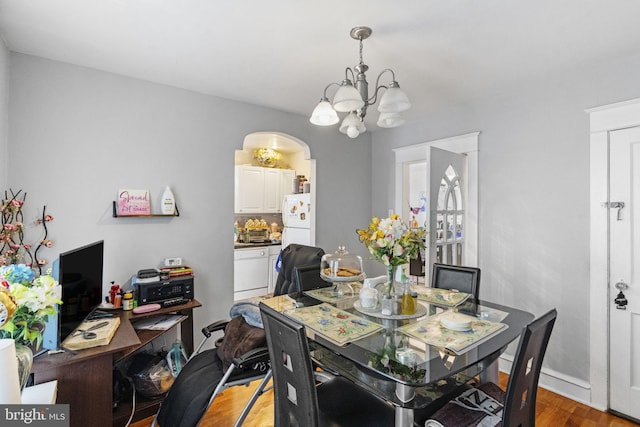 dining room with an inviting chandelier, light wood-style floors, arched walkways, and baseboards