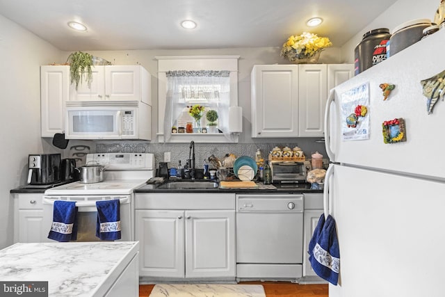 kitchen with a sink, white appliances, tasteful backsplash, and white cabinetry