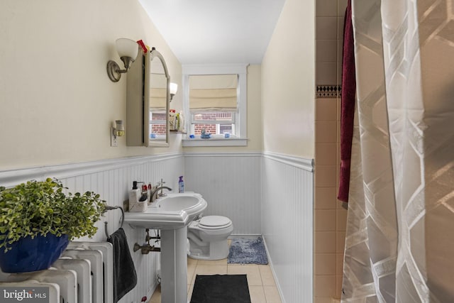 bathroom with tile patterned floors, a wainscoted wall, radiator, and toilet