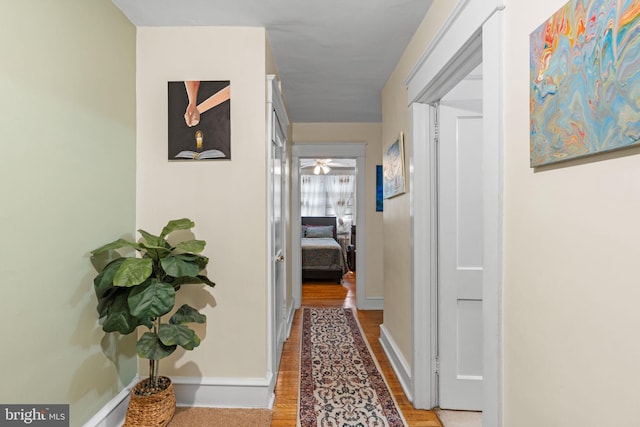 corridor featuring baseboards and wood finished floors