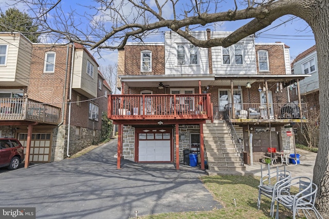 view of front facade featuring stairs, brick siding, a garage, and driveway