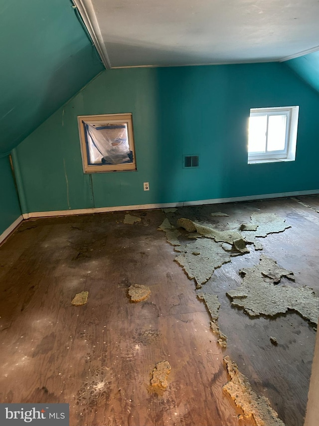 additional living space with visible vents, lofted ceiling, baseboards, and wood finished floors