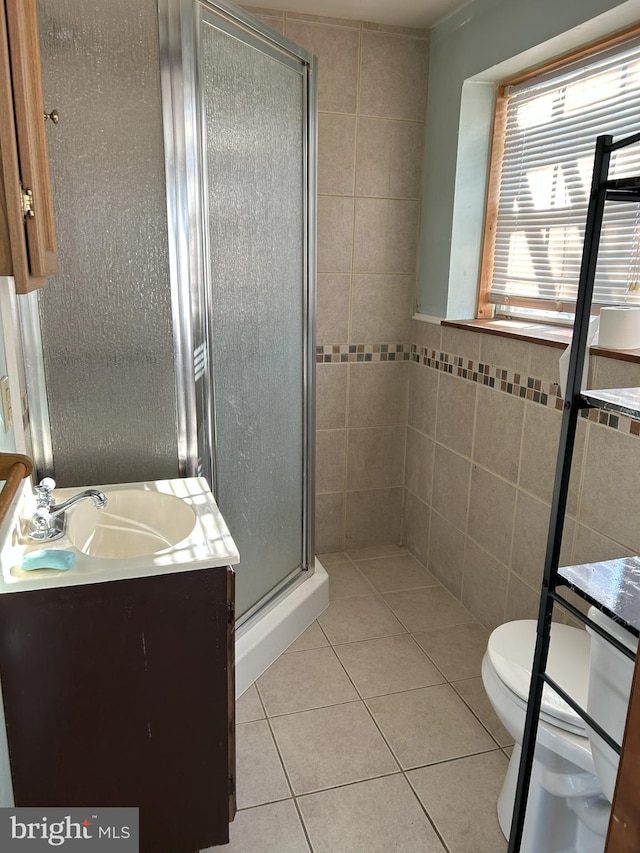 bathroom featuring vanity, a stall shower, tile patterned flooring, tile walls, and toilet