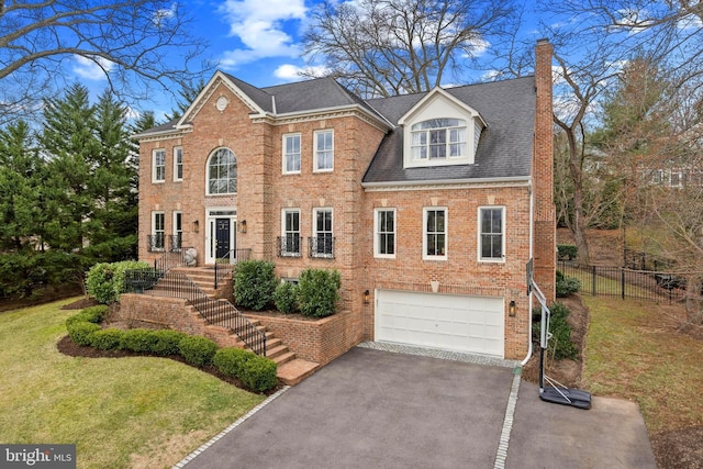 view of front facade featuring a front yard, stairway, a chimney, aphalt driveway, and brick siding