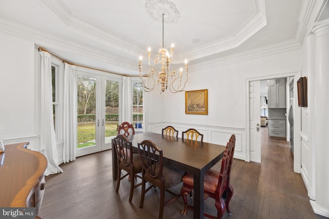 dining space with a tray ceiling, dark wood-type flooring, wainscoting, and french doors