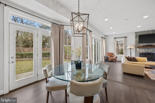 dining area featuring recessed lighting, a notable chandelier, wood finished floors, and a fireplace