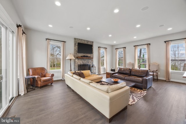 living room with recessed lighting, baseboards, a stone fireplace, and wood finished floors