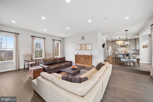 living area with visible vents, dark wood-type flooring, a notable chandelier, recessed lighting, and baseboards