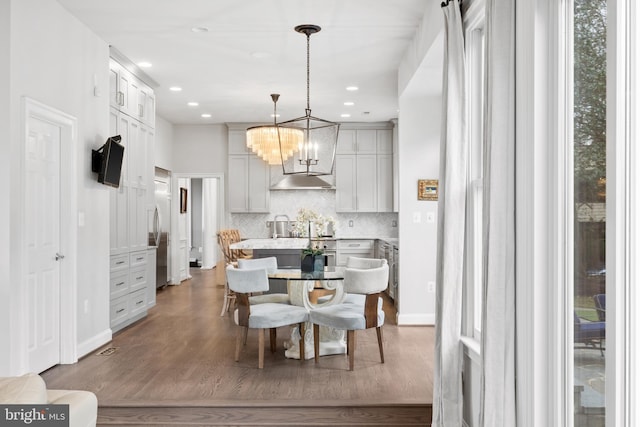 kitchen with wood finished floors, a kitchen island, decorative backsplash, light countertops, and hanging light fixtures