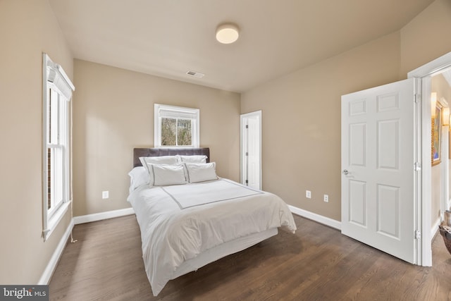 bedroom with dark wood finished floors, visible vents, and baseboards