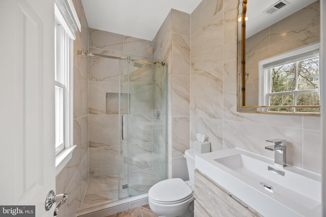 bathroom featuring visible vents, toilet, a stall shower, and tile walls