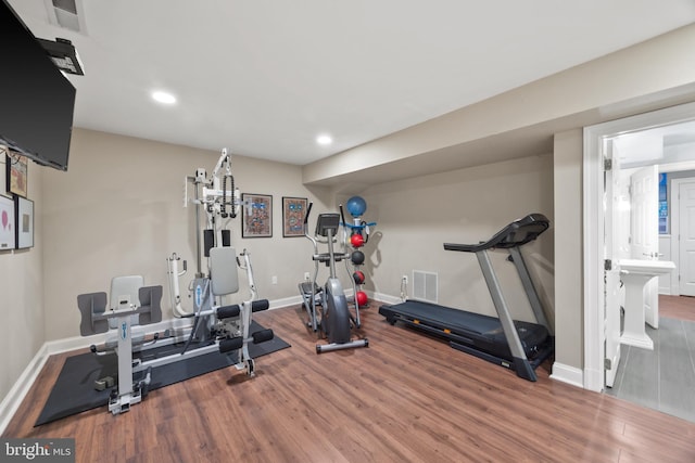 exercise room featuring visible vents, baseboards, and wood finished floors