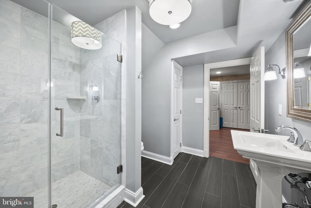 bathroom with a shower stall, toilet, baseboards, and wood tiled floor