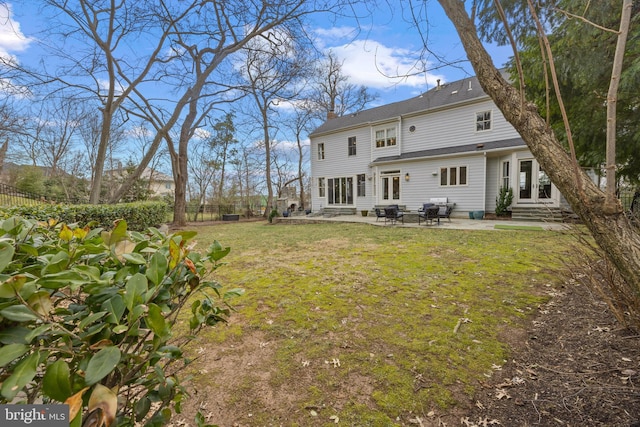 back of property with a lawn, entry steps, a patio, fence, and a chimney