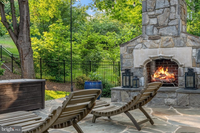 view of patio / terrace featuring an outdoor stone fireplace and a fenced backyard