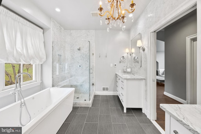 bathroom featuring visible vents, baseboards, a stall shower, a soaking tub, and vanity