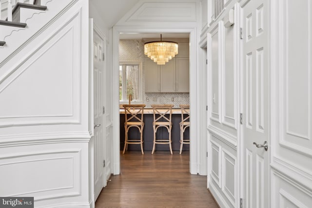 corridor with a notable chandelier and dark wood-style flooring