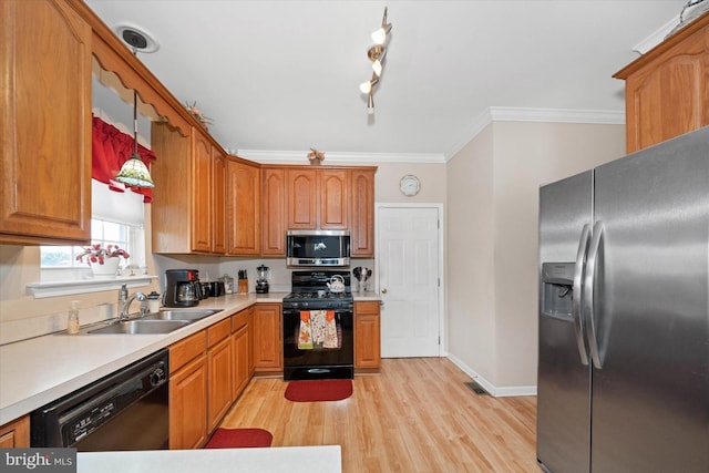 kitchen featuring crown molding, light wood finished floors, light countertops, a sink, and black appliances