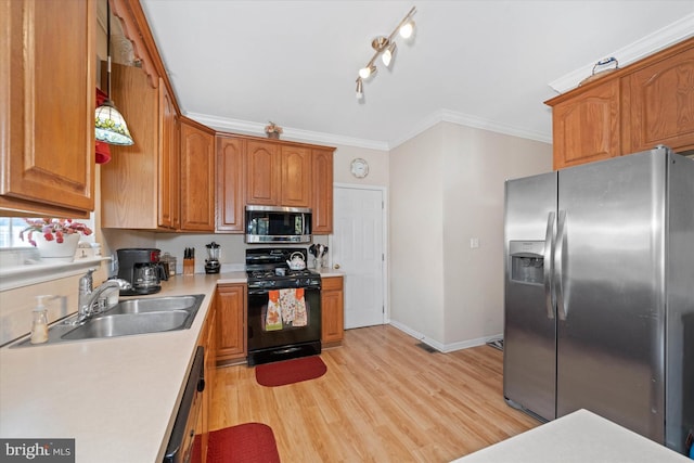 kitchen featuring light wood-style flooring, appliances with stainless steel finishes, light countertops, crown molding, and a sink