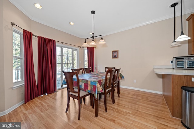 dining room featuring light wood-type flooring, plenty of natural light, and ornamental molding