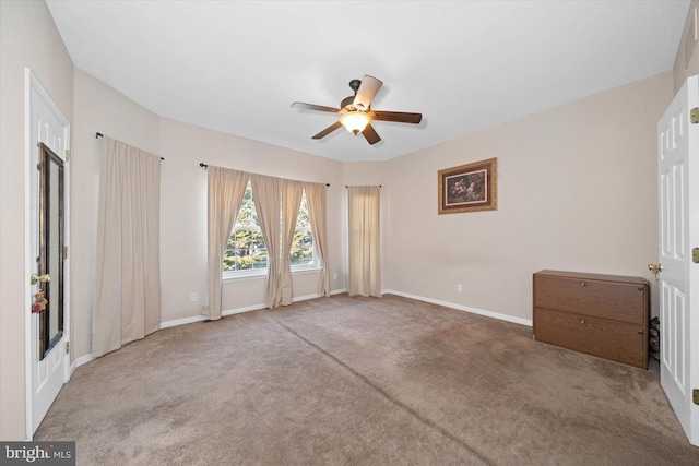 carpeted spare room with ceiling fan and baseboards