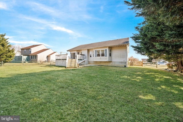 rear view of property featuring fence and a lawn