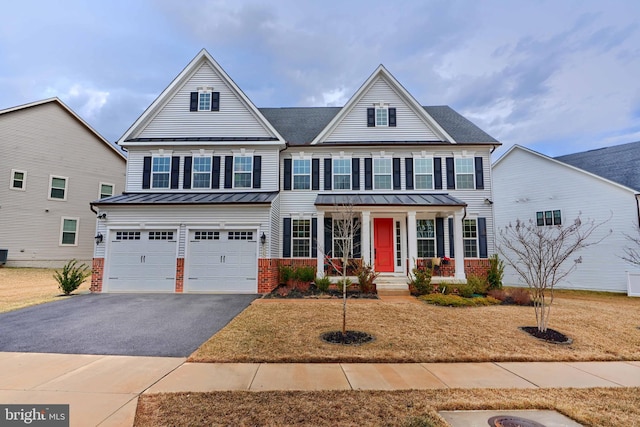 view of front facade featuring driveway, a garage, a standing seam roof, covered porch, and brick siding