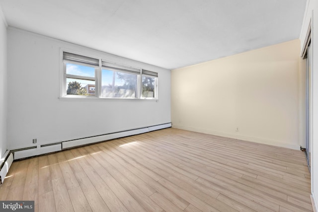 spare room featuring baseboards, baseboard heating, and light wood finished floors