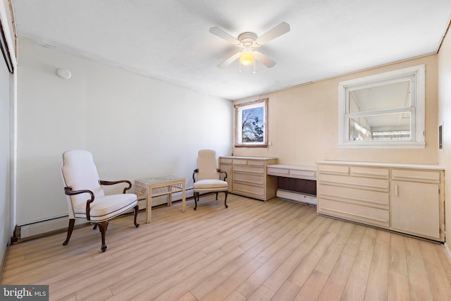 sitting room featuring a ceiling fan, light wood-style floors, and built in desk