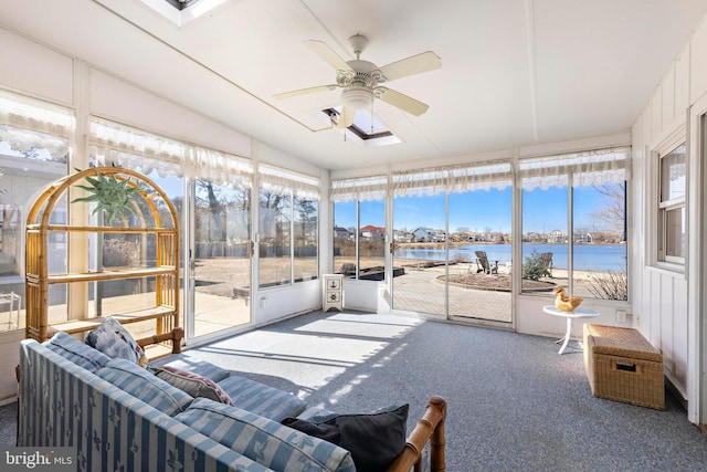 sunroom / solarium featuring a water view, a healthy amount of sunlight, lofted ceiling with skylight, and a ceiling fan