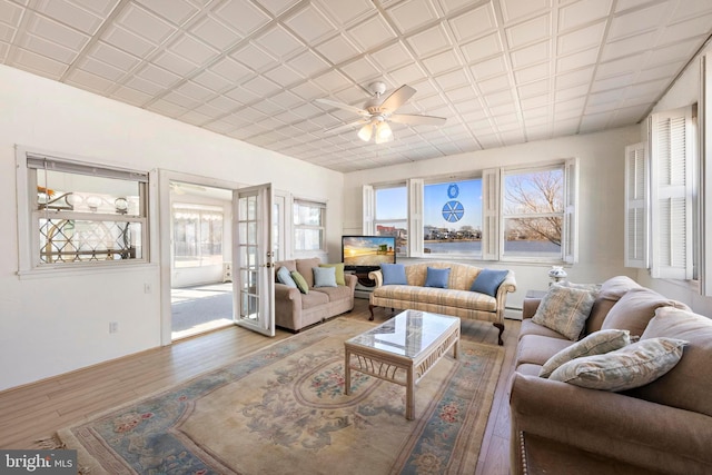 living room with a ceiling fan, wood finished floors, french doors, and a healthy amount of sunlight