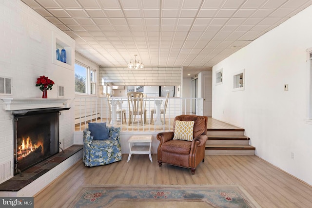 living area featuring wood finished floors, a fireplace, visible vents, and a chandelier