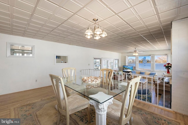 dining room with ceiling fan with notable chandelier, an ornate ceiling, wood finished floors, and a wealth of natural light