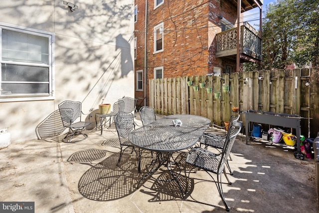 view of patio featuring a balcony and fence